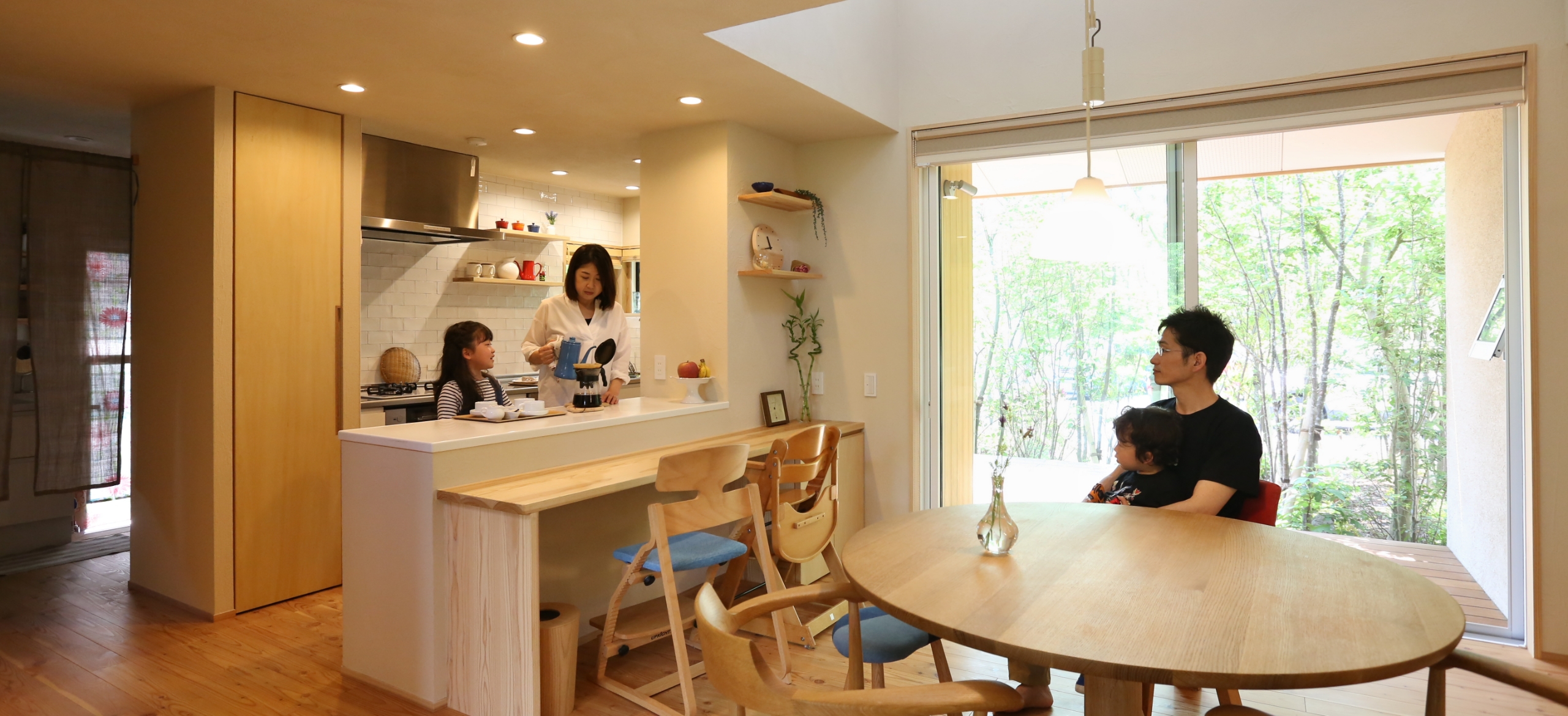 キッチンに立つ母と娘・椅子に座っている父と息子の写真