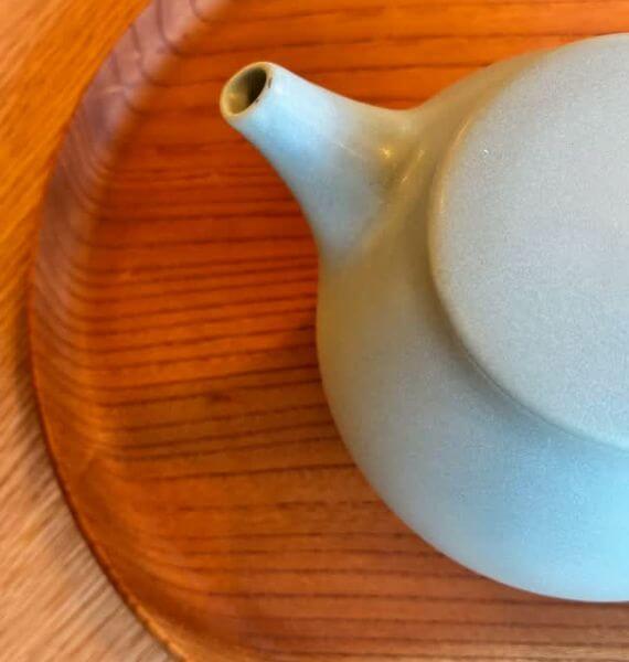 木目のラウンドトレーに置かれた、陶器急須を俯瞰した様子