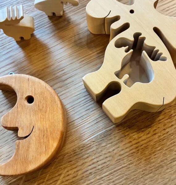 木目のテーブルに笑顔の三日月と、トナカイ形のくり抜きがある木製おもちゃが並ぶ様子